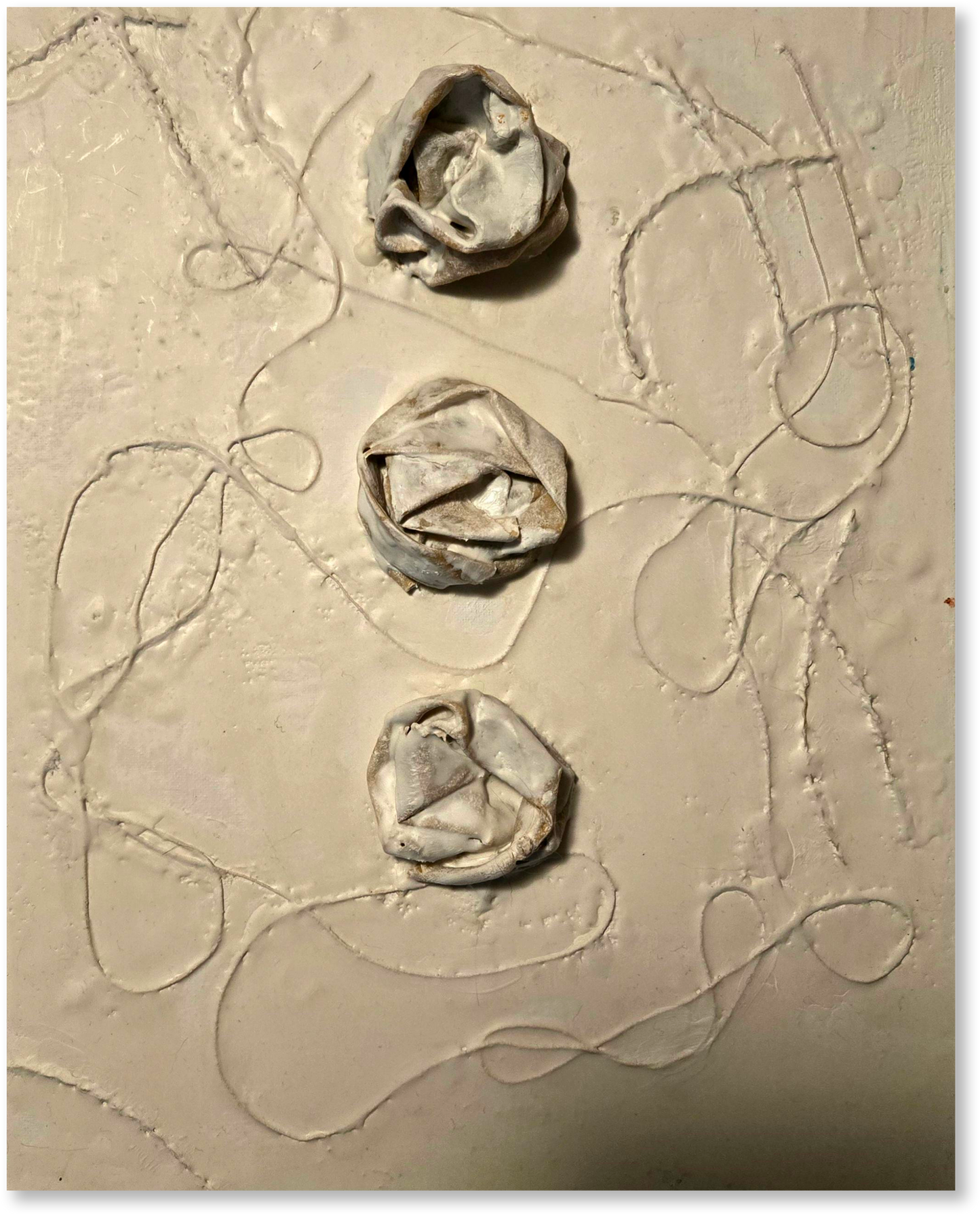 Three clay flower shapes on a textured beige surface with abstract lines.
